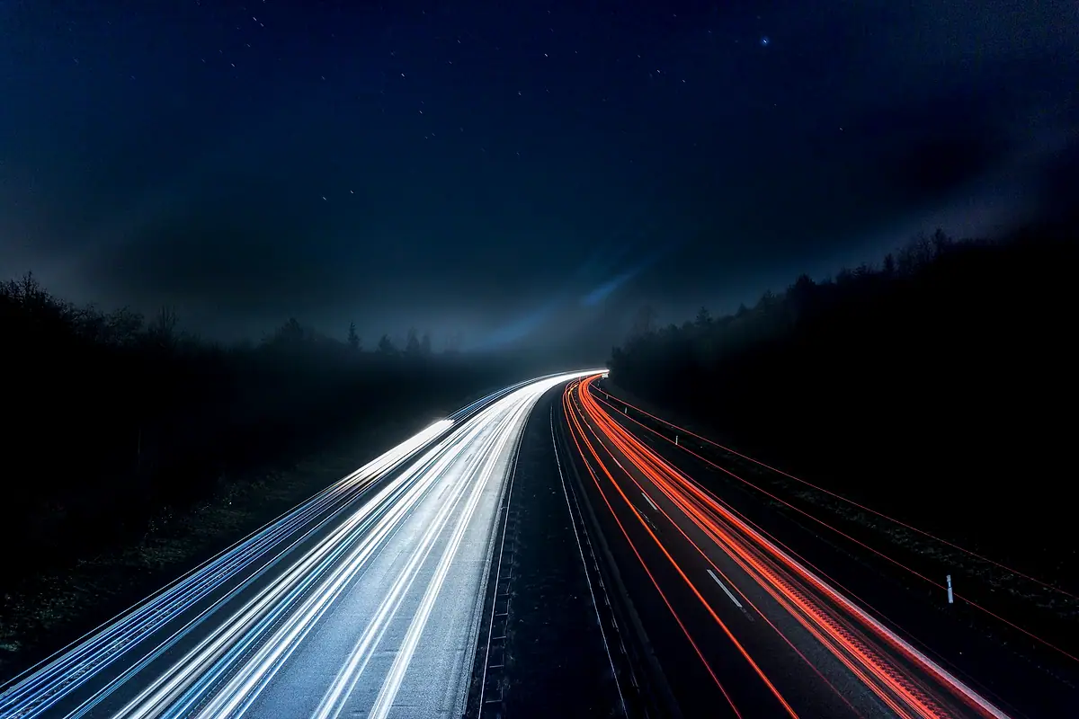 Long-exposure light trails from traffic on a highway at night.