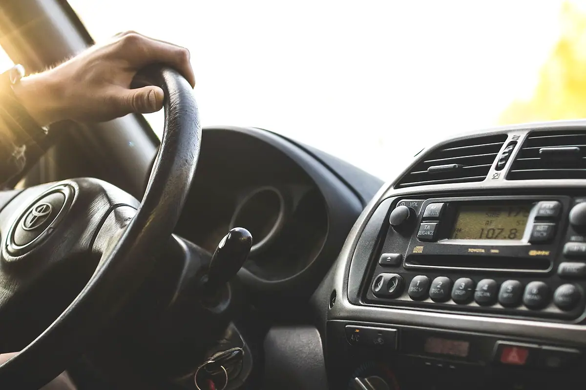 A driver's hand on the steering wheel of a car.