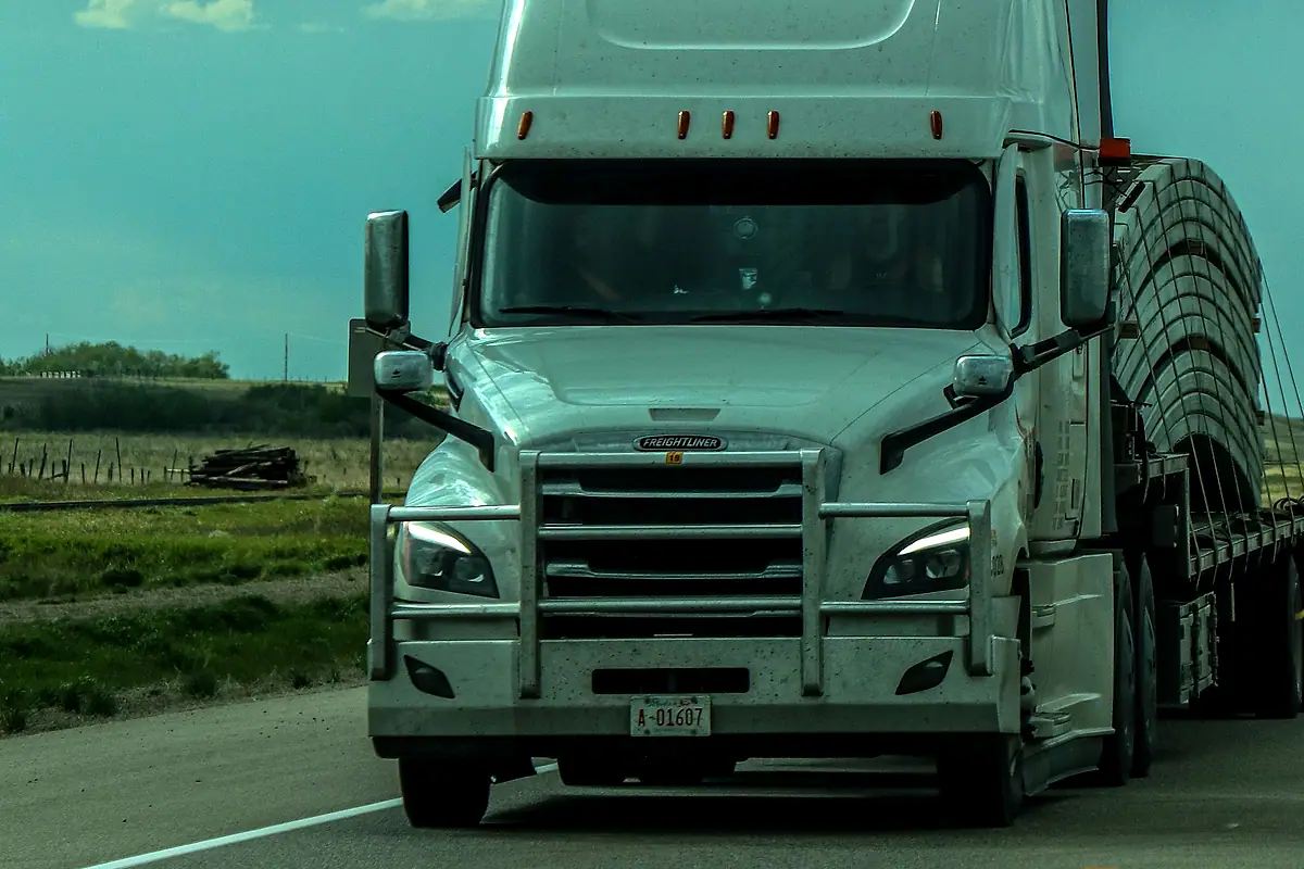A white tractor unit pulling a trailer on a two-lane road.
